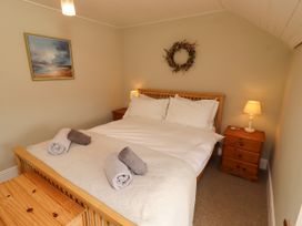 A bedroom with a bed and nightstand at Coble Cottage Craster