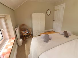 A bedroom with a bed, wardrobe, and chair at Coble Cottage in Craster