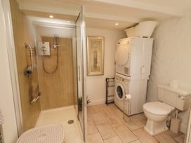 A bathroom with a shower, toilet, and laundry appliances at Coble Cottage Craster