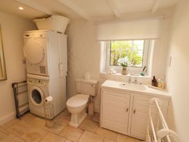 A bathroom with a washing machine, dryer, toilet, and sink at Coble Cottage in Craster