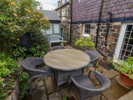 A garden with a round table and chairs at Coble Cottage in Craster
