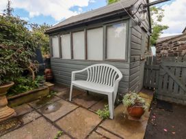 A garden with a plastic chair and a shed at Coble Cottage in Craster