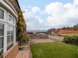 A view of a garden with a bench and flowers at Coble Cottage in Craster