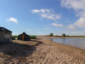 A beach scene with a shed and water at Percy Cottages No4 in Alnmouth