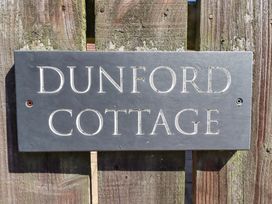A nameplate reading Dunford Cottage on a wooden fence in Bamburgh