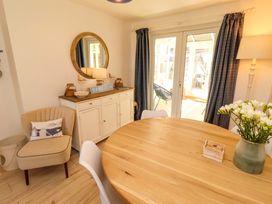 A dining room with a round table and sideboard at Dunford Cottage Bamburgh
