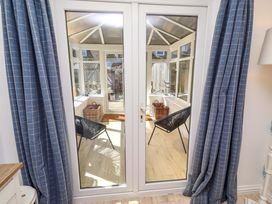 A conservatory with chairs and doors at Dunford Cottage Bamburgh