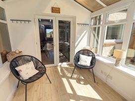A conservatory with two chairs and a lamp at Dunford Cottage in Bamburgh
