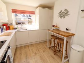 A kitchen with a sink and stools at Dunford Cottage in Bamburgh