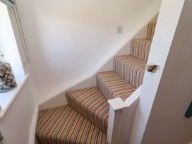 A staircase with striped carpet and window at Dunford Cottage Bamburgh