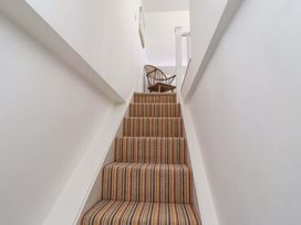 A staircase with striped carpet and a chair at Dunford Cottage Bamburgh