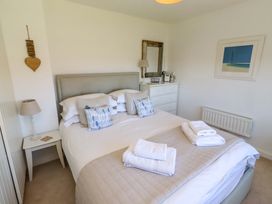 A bedroom with a bed and dressers at Dunford Cottage in Bamburgh