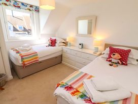 A bedroom with two beds, a dresser, and toys at Dunford Cottage, Bamburgh