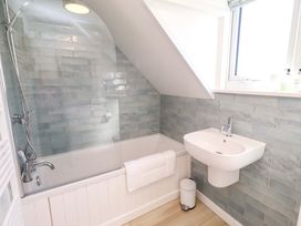 A bathroom with a bathtub, sink, and window at Dunford Cottage in Bamburgh