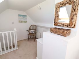 A landing with a wooden stool and a mirror at Dunford Cottage in Bamburgh