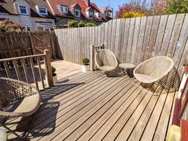 An outdoor deck area with chairs and a table at Dunford Cottage in Bamburgh