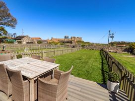 A garden with a seating area and a view of a castle at Dunford Cottage in Bamburgh