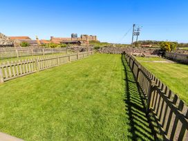 A garden with grass and a wooden fence at Dunford Cottage Bamburgh