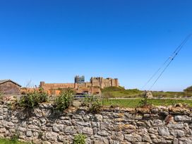 A castle view with a stone wall and shed at Dunford Cottage Bamburgh