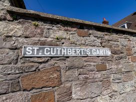 A street sign labeled St. Cuthbert's Garth on a stone wall