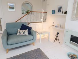 A living room with a chair, table and lamp at Dell Point in Beadnell