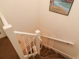 A staircase with handrail and artwork at Old Bakery No2 Seahouses