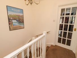A staircase with wall art and a door at Old Bakery No2 Seahouses