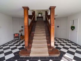 A staircase with a wooden banister in a hallway at Treetops, Alnwick