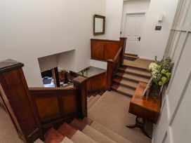 A staircase and hallway with a mirror and flowers at Treetops, Alnwick