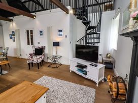 A living room with a spiral staircase and television at Treetops, Alnwick