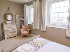 A bedroom with a bed and armchair at Treetops, Alnwick