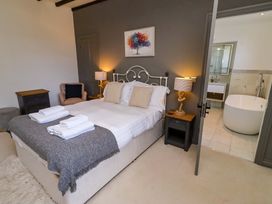 A bedroom with a bed and an en-suite bathroom at Treetops, Alnwick