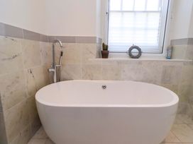 A bathroom with a bathtub and window at Treetops, Alnwick