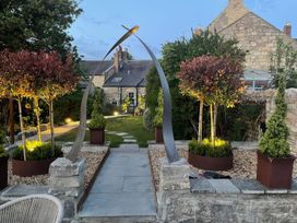 A garden with a sculpture and trees at Westhill House Warkworth