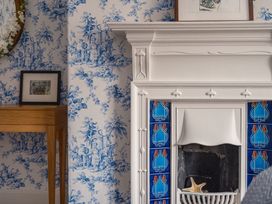 A living room with a fireplace and decorative wallpaper at Westhill House in Warkworth