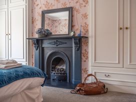 A bedroom with a fireplace and mirror at Westhill House Warkworth