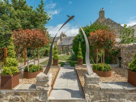 A garden with trees, sculpture, and pathway at Westhill House in Warkworth