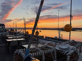 An outdoor scene with tables and chairs along the water at Westhill House in Warkworth
