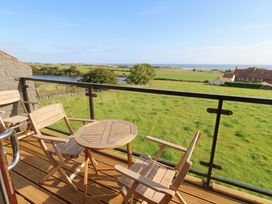A balcony with a table and chairs overlooking the ocean at Links View in Embleton