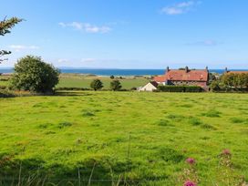 A view of a house and ocean from a field at Links View in Embleton