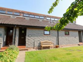 A house exterior with a bench and lawn at Links View in Embleton