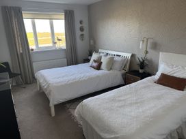 A bedroom with two beds and a window at Sea Croft in Beadnell