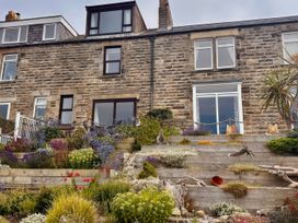 A garden with a stone building and plants at Old Coastguard Cottages in Amble
