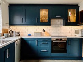 A kitchen with cabinets and appliances at Old Coastguard Cottages Amble