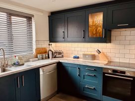 A kitchen with cabinets and appliances at Old Coastguard Cottages Amble