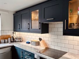 A kitchen with blue cabinets and appliances at Old Coastguard Cottages Amble
