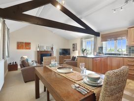 A living room with a kitchen, dining table and television at Plumtree Cottage in Alnmouth