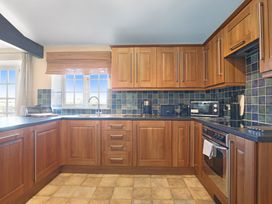 A kitchen with wooden cabinets and appliances at Plumtree Cottage in Alnmouth