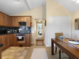 A kitchen with wooden cabinets and dining table at Plumtree Cottage in Alnmouth