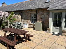 An outdoor area with a wooden table and benches at Beachward in Embleton